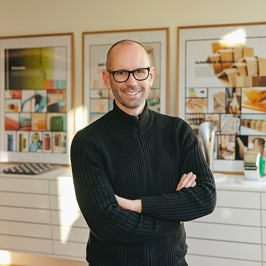 Vorwerk: Foto: Das Foto zeigt einen Oberkörper-Ausschnitt von Jan Delfs, Vorwerk Chefdesigner, mit vor dem Bauch verschränkten Armen, der in die Kamera lächelt.